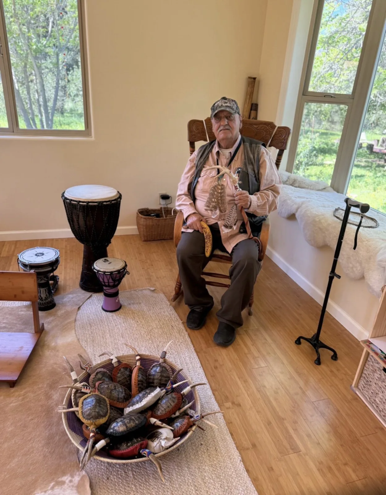 A visiting elder seated with a handmade dreamcatcher and drum