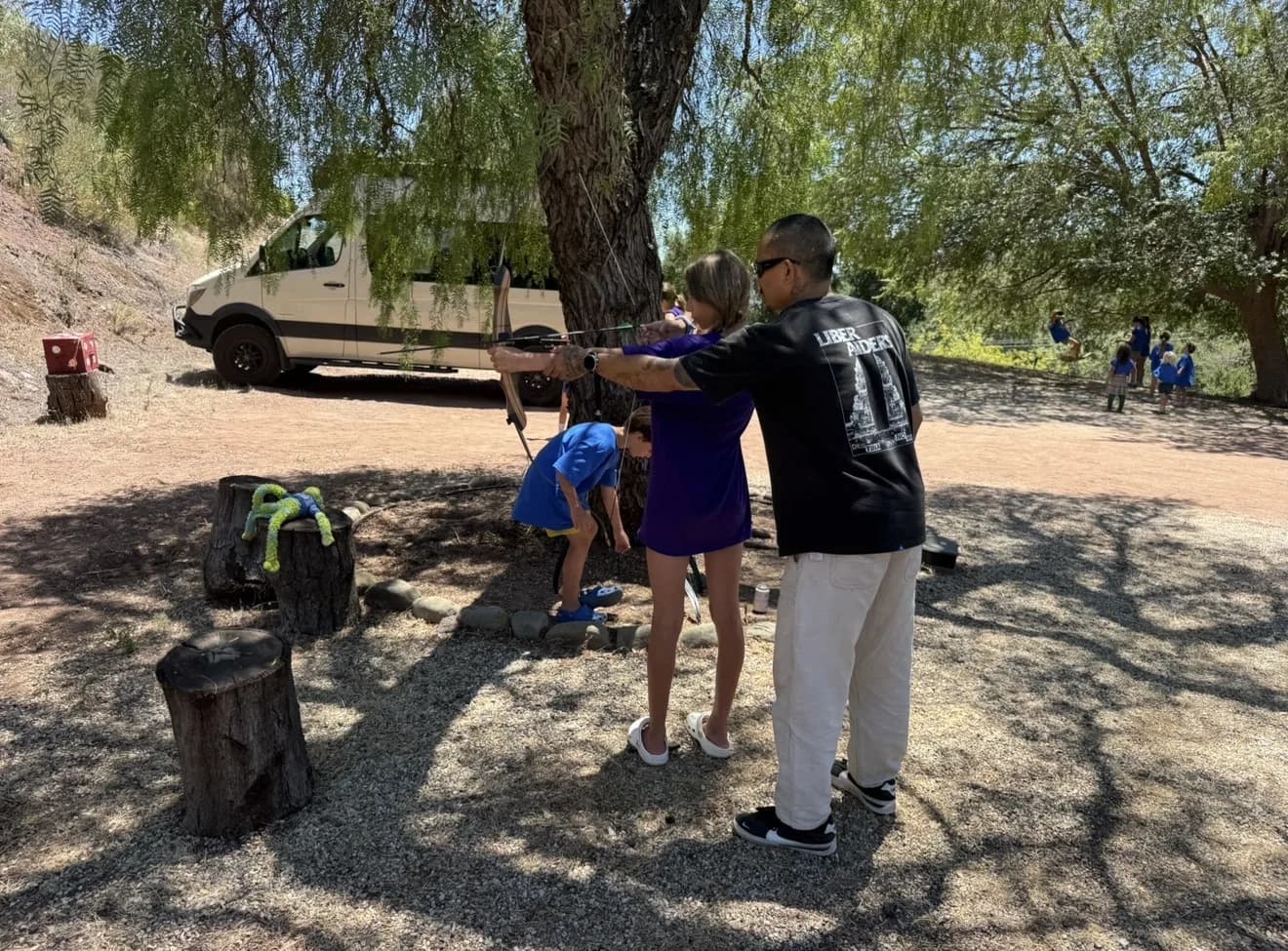 A guide helping a child practice focused archery outdoors