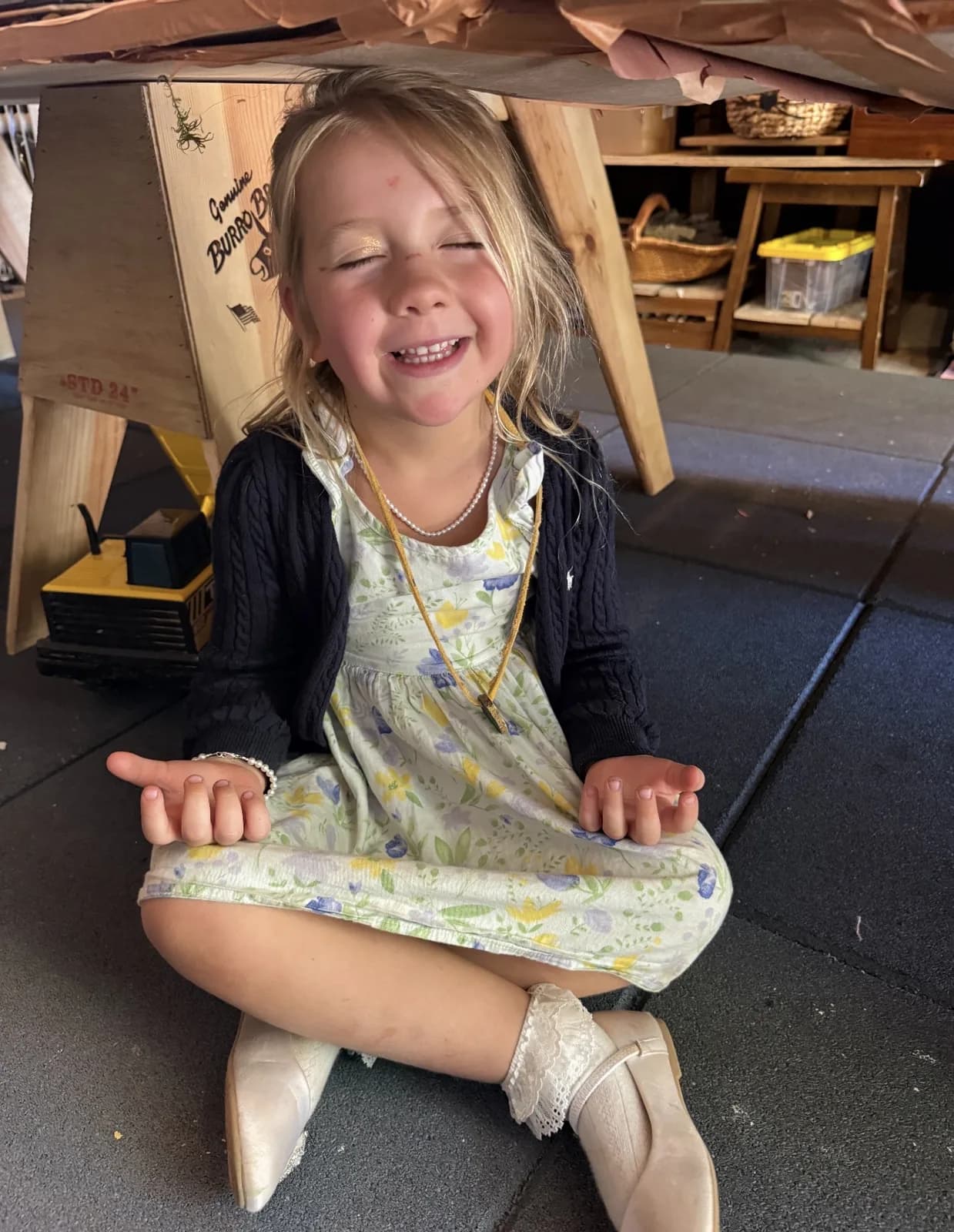 A smiling child seated cross-legged with eyes gently closed