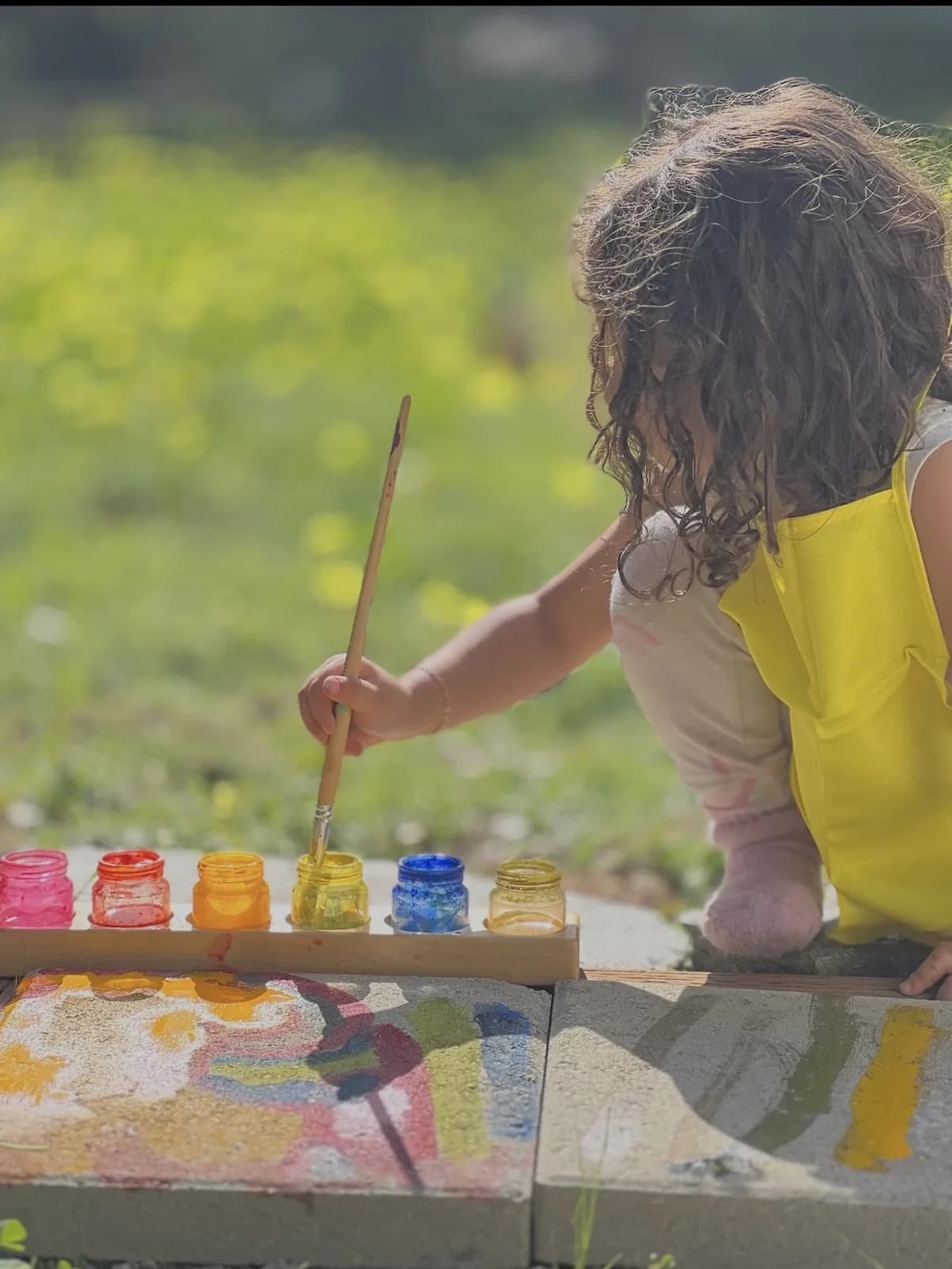 A child painting outdoors with a bright line of colors