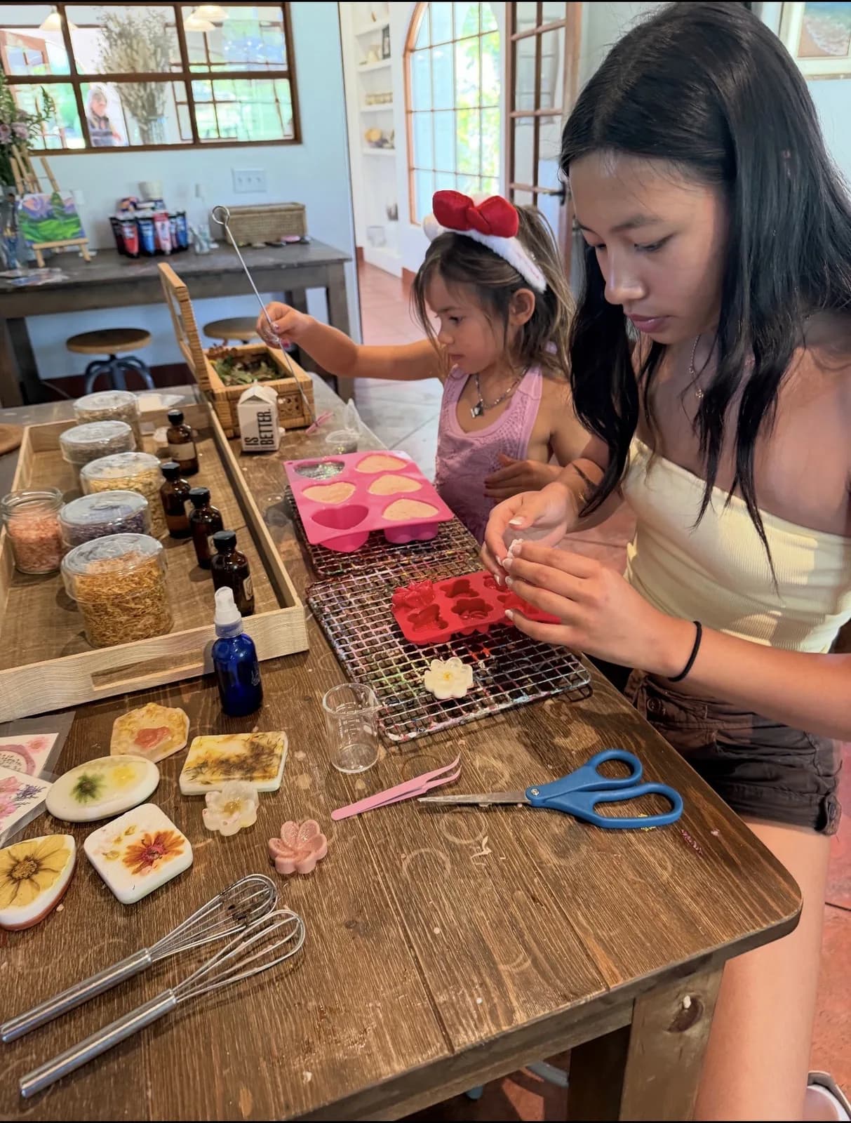 An older child helping a younger child complete a detailed craft project