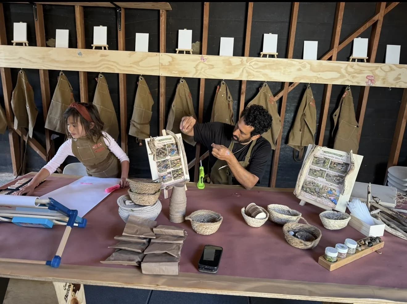 A guide and a young child working side by side at the MANA makers station
