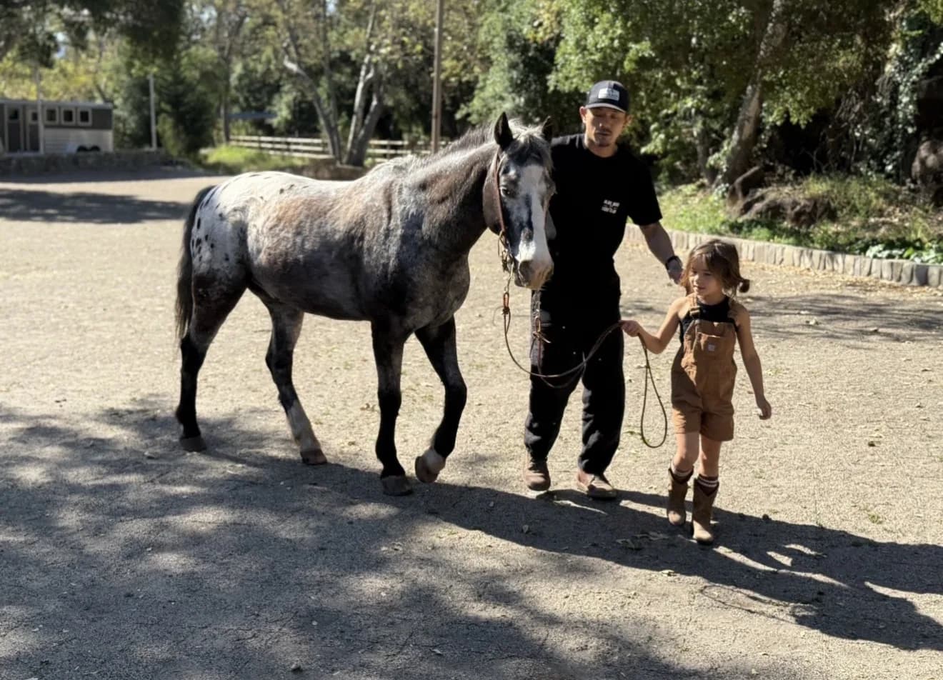 A child learning to lead a horse with a guide alongside