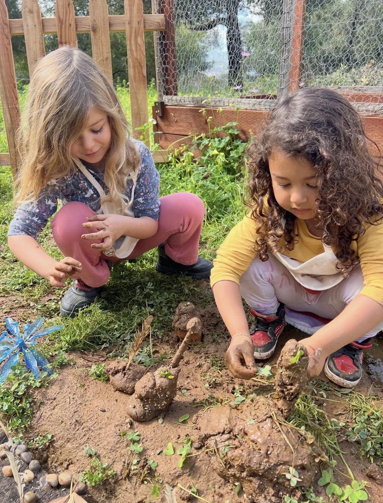Two children shaping figures from earth during outdoor play
